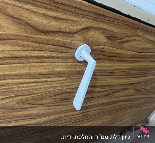 ידית דלת לבנה על דלת עץ